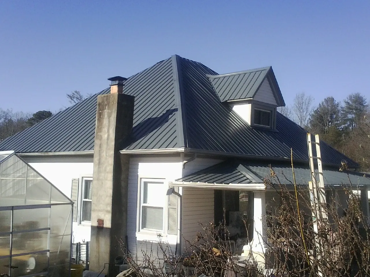 Dark blue standing seam metal roof on a white farmhouse with dormer — Slate & Tile Roof Repair by Roofing Brothers in Clarks Mills