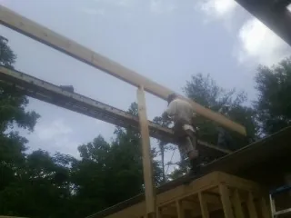 Carpenter setting a ridge beam over a new addition frame — Ice Dam Removal by Roofing Brothers in Clarks Mills