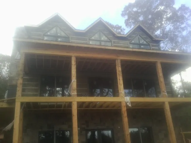 Dormers and porch framing on a large log home under construction — Roof Coating work by our crew in Clarks Mills