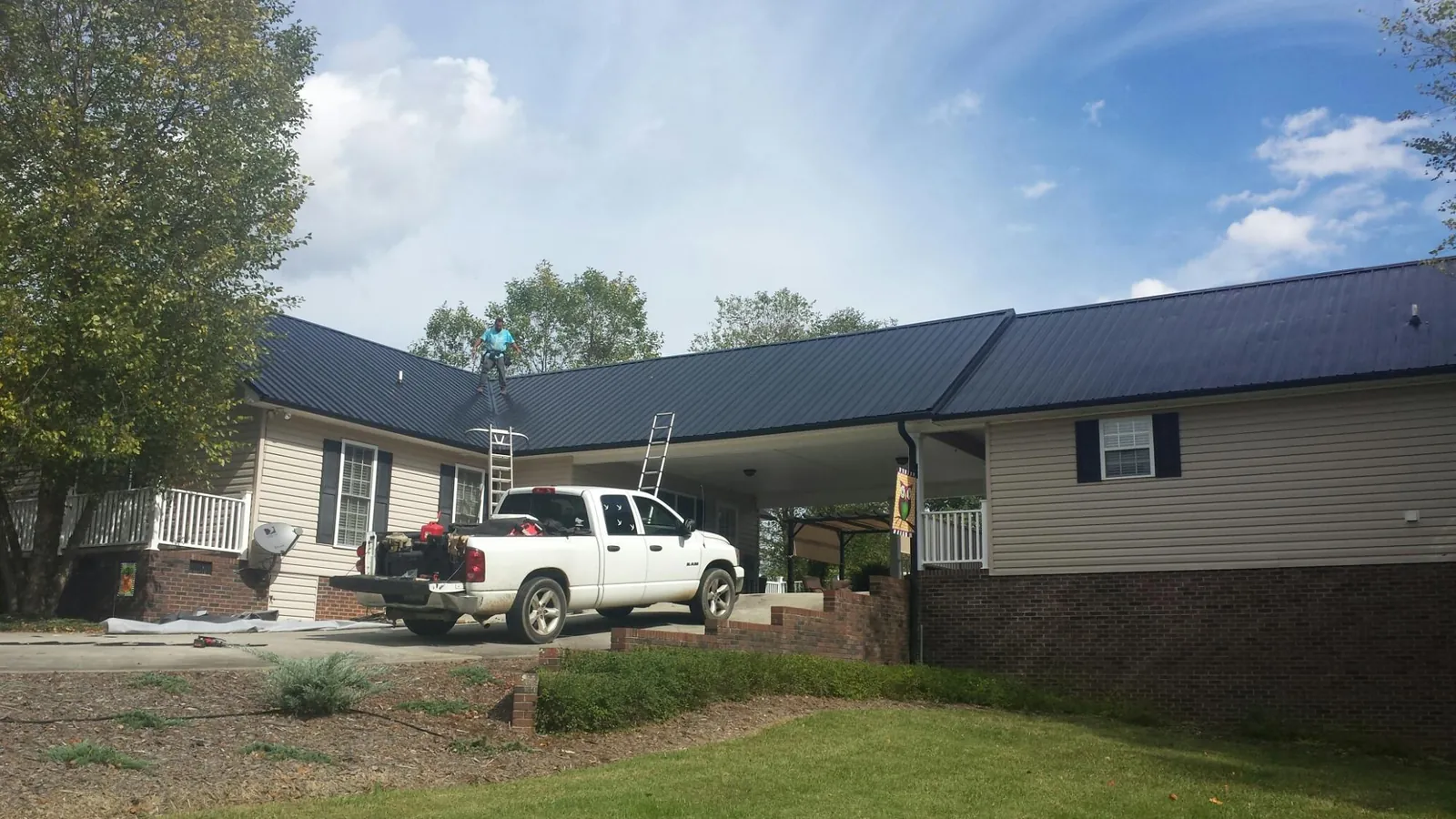 Black metal roof over a home and attached breezeway with ladders set in Clarks Mills