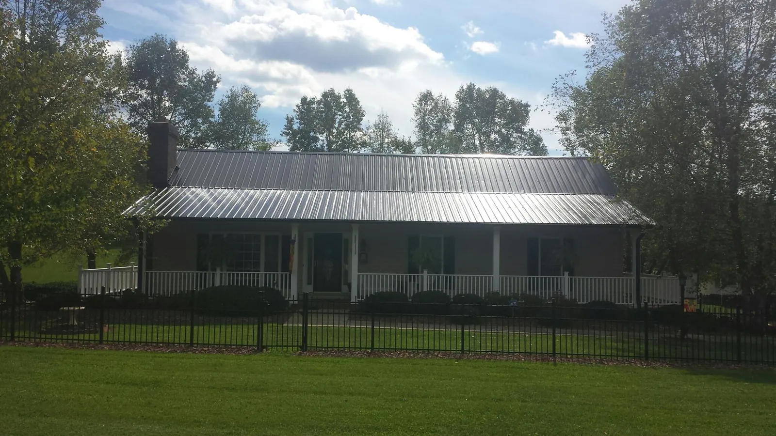 Gray metal roof on a brick ranch with a full width front porch — Gutter Guard Installation work by our crew in Clarks Mills