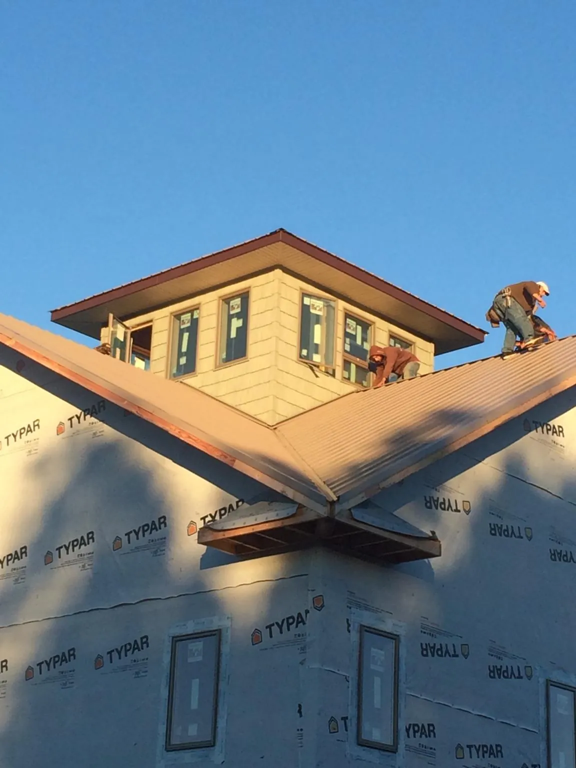 Roofers working around a rooftop cupola on a new metal roof at sunset — Roof Waterproofing in Clarks Mills by Roofing Brothers